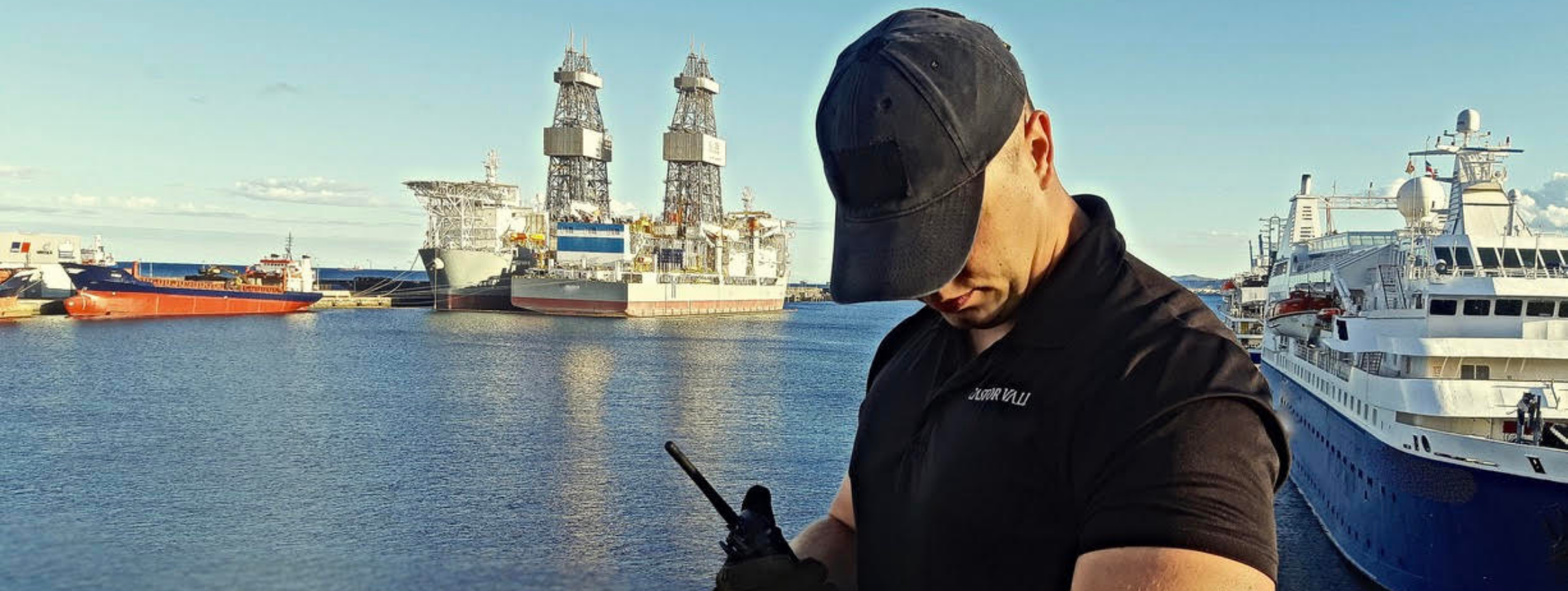 Castor Vali Security Liaison personnel looking at watch infront of ships at sea.